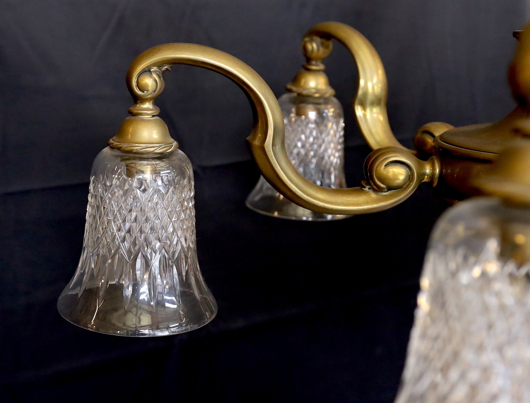 An early 20th century English bronze six light chandelier with cut glass shades, drop 70cm. width 80cm